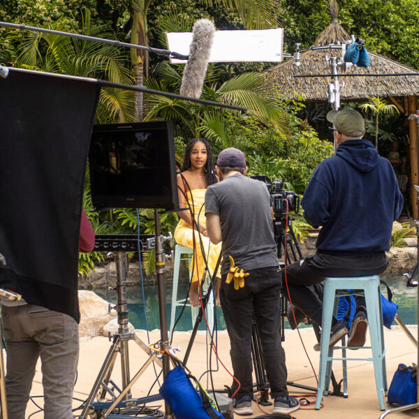 Production set with crew recording talent interview in front of Lagoon pool and dense jungle background at Tropic Shots production set