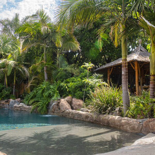 Empty Baja shelf beach entry lagoon pool with waterfalls and dense jungle backdrop at Tropic Shots production set