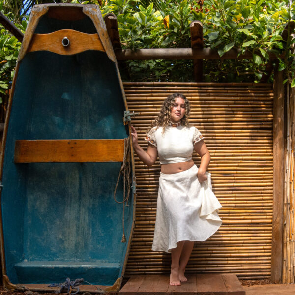 Model standing in front of decorative bamboo wall with blue boat backdrop at Tropic Shots production set