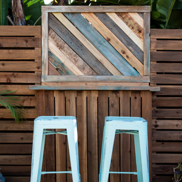 Decorative wood wall with mini bar and two barstools at Tropic Shots production set
