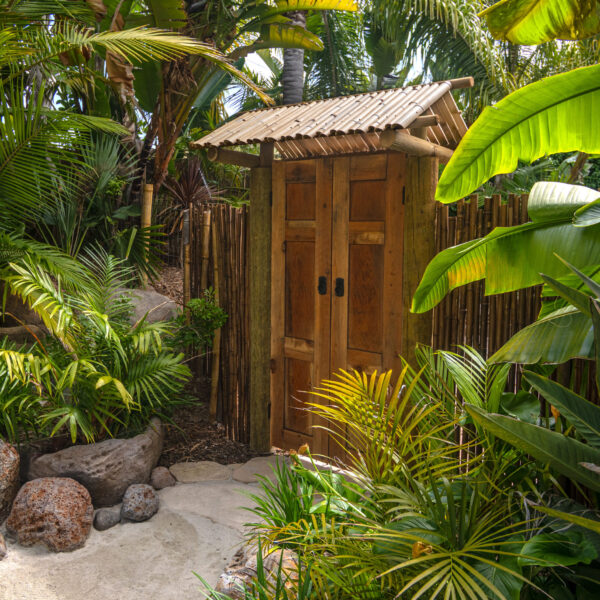 Authentic Bali garden gate with bamboo roof and bamboo fence surrounded by palms and tropical foliage at Tropic Shots production set