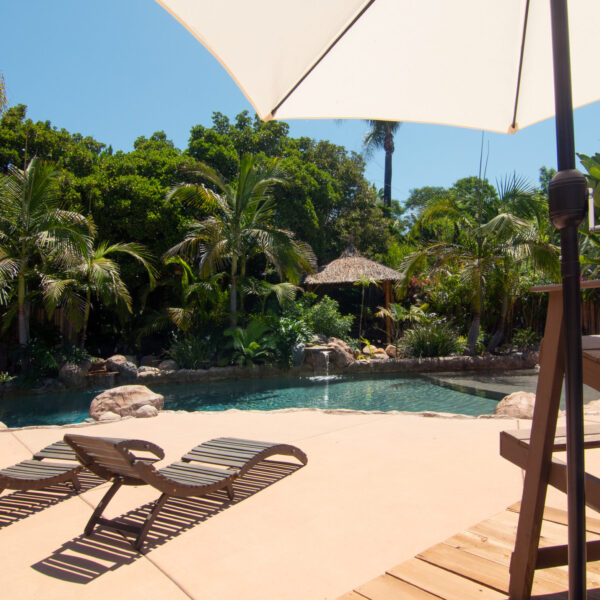 Wide angle shot of surrounding lagoon pool area with lagoon pool and tropical footage, trees and Palm Grove background at Tropic Shots production set