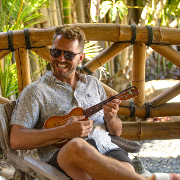 Talent play ukulele in a bamboo accented Palapa at Tropic Shots production set
