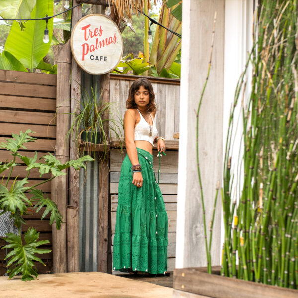 Model standing in front of decorative wood wall and café with bamboo accents and tropical sign at Tropic Shots production set
