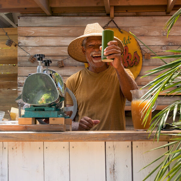Man preparing fresh-pressed sugarcane juice at our outdoor tropical bar at Tropic Shots production set.